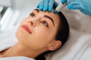 clinician using hydrafacial wand on woman’s forehead