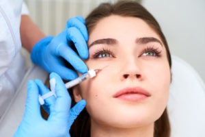 clinician injecting filler under woman’s eye