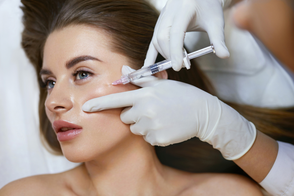 Close-up of a woman receiving a cosmetic injection in her cheek by a professional wearing gloves, highlighting facial aesthetics and beauty treatments.